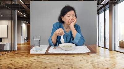 Elderly asian woman bored with food Wall mural