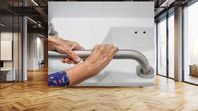 Elderly woman holding on handrail in bathroom Wall mural