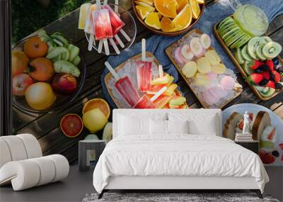 Outdoor summer setting with a selection of homemade frozen desserts like fruit popsicles, sorbets, and ice cream sandwiches  Wall mural