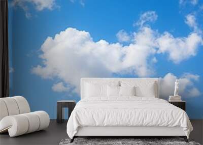 A bright blue sky with fluffy white clouds scattered across it. Wall mural