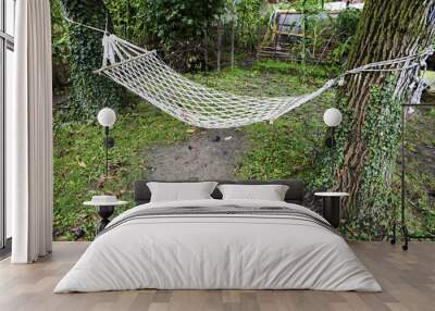 Comfortable mesh hammock stretched between two trees in a green garden Wall mural