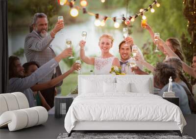 Young couple their guests toasting champagne during wedding reception in garden Wall mural