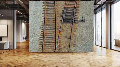 Two sets of vintage railway tracks dividing into a V-shape with a control box on gravel.  Wall mural