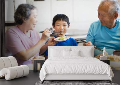 Grandmother feeding her grandson in restaurant. Wall mural