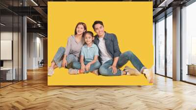 Happy Asian young family with one child sitting  and smiling at camera isolated on yellow Wall mural