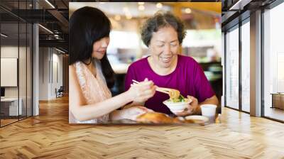 Happy  daughter and senior mother enjoy eating in restaurant Wall mural