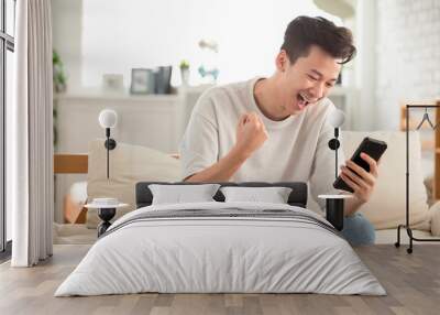 happy young man  looking at cell phone celebrate receiving  good news Wall mural