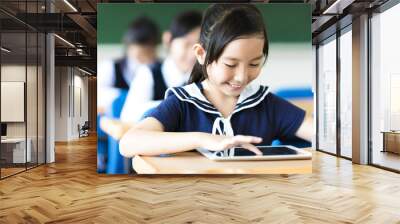 smiling little girl using tablet pc in classroom Wall mural