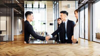 Young business people shaking hands in the office Wall mural