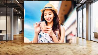 young charming asian woman holding shopping bags ans watching mobile phone on the street Wall mural