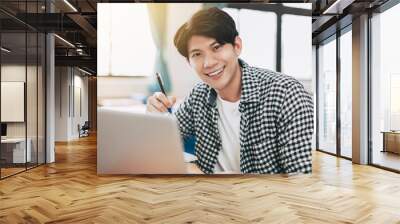 Young cheerful asian student studying in classroom Wall mural