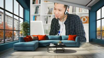 young man  wear headset and using video conference  on laptop computer at home Wall mural