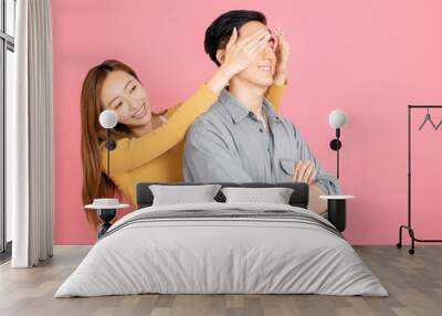 young woman covering man’s eyes to surprise him Wall mural