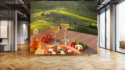 Italian pizza with glasses of white wine against Tuscan vineyards near the Florence in Italy Wall mural