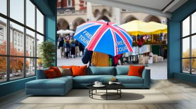 Free tour on a Cracow market square, a UK english guide with a united kingdom flag umbrella seen from the back. Local free of charge tourist guides. Tourism, travelling for england residents concept Wall mural