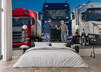 Two semi truck drivers shaking hands on a truck stop Wall mural