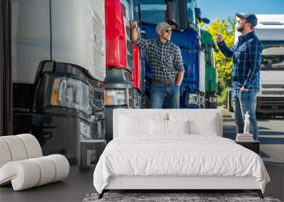 Two Truckers Standing Next to a Row of Semi Trucks Wall mural