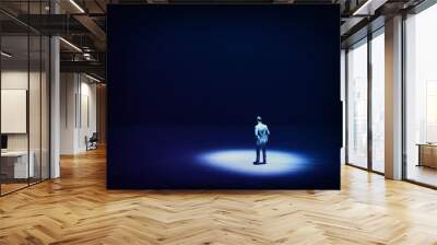 A picture of a miniature man stands in the spotlight looking forward.Concept of facing the unknown, taking a decision and finding solution. Wall mural