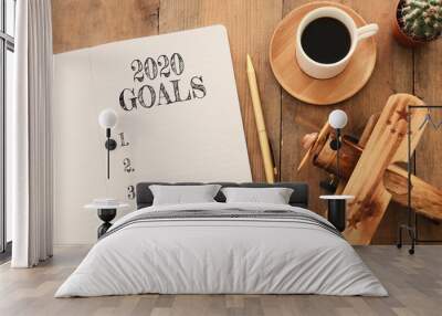 Business concept of top view 2020 goals list with notebook, cup of coffee and old plane toy over wooden desk Wall mural