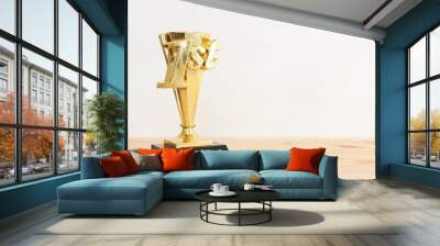 Golden trophy on wooden table. Idea of award and success Wall mural