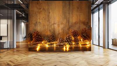 holiday image with christmas golden garland lights and pine cones over wooden background Wall mural