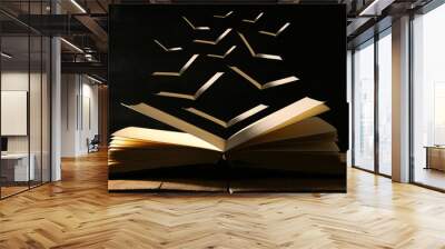 image of open antique book over wooden table with flying pages. Wall mural