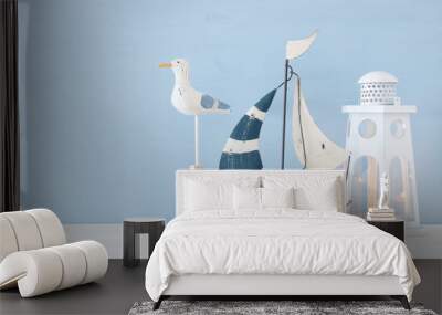 nautical concept image with white decorative seagull bird, boat and lighthouse lantern over light blue background. Wall mural