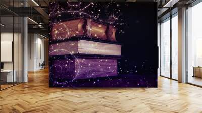 stack of antique books on old wooden table. fantasy medieval period and religious concept. Glitter sparkle lights Wall mural