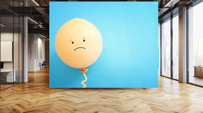 Top view image of balloon with sad face over blue background. Concept of emotions and sadness or stress Wall mural