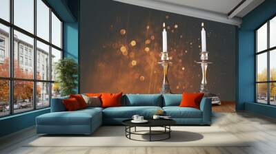 two candlesticks with burning candles over wooden table and vint Wall mural