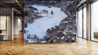 Aerial shot of the frozen lake of Alleghe, houses and snowy town, snow on the roofs. Water lying on the doomites and on Mount Civetta. Wall mural