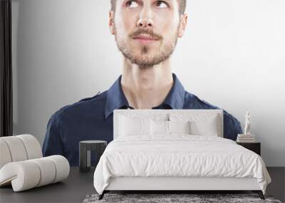 closeup of young man looking up thinking on white background Wall mural