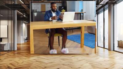 African businessman having video call on laptop working in underwear at home office Wall mural