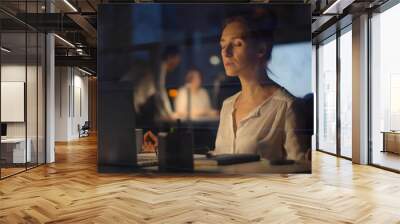 Businesswoman relaxing and meditating sitting at workplace in modern office at night Wall mural