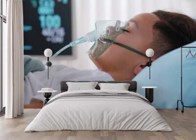 Close up sick young african boy with face oxygen mask sleeping in bed at hospital. Wall mural