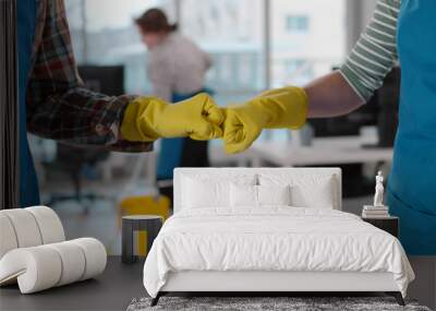 Cropped shot of janitors bumping fists in rubber gloves cleaning office Wall mural