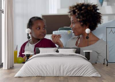 Cute african girl visiting sick mother in hospital at lunch time Wall mural