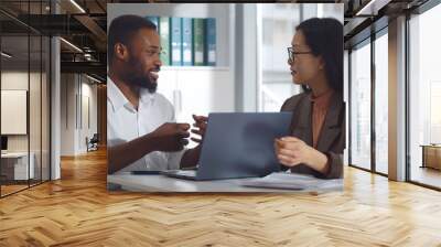 Diverse business colleagues looking at laptop and discussing project in office Wall mural