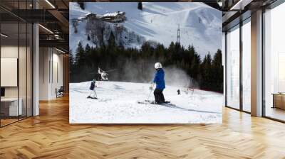 Child, watching rescue action on ski slope, helicopter picking up injured person from ski slope Wall mural