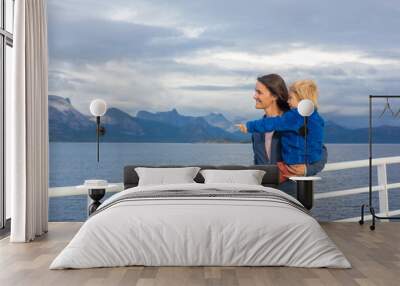 Child and mom, cute blond boy with mother, looking at the mountains from a ferry in Nortern Norway on his way Wall mural