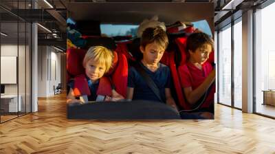 Children, traveling to vacation with car, sitting in carseats and reading books and playing on mobile Wall mural