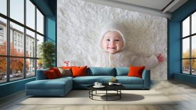 Close portrait of a little baby boy in white knitted onesie and a hat Wall mural