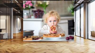 Cute little toddler child, eating homemade plum pie at home Wall mural