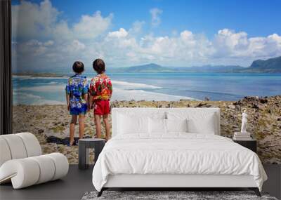 Happy children in colorful hawaiian shirts, enjoying observing the big waves on shore of an island near Mauritius Wall mural