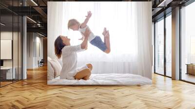 Mother, playing with her preschool child at home in bed, having fun Wall mural