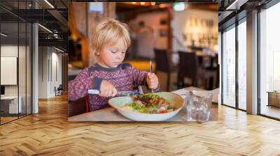 Preschool child, cute boy, eating lamb meat in a restaurant, cozy atmosphere, local small restaurant in Tromso, Norway Wall mural