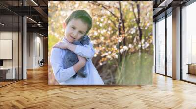 Preschool child, cute boy, playing with little rabbit outdoors Wall mural