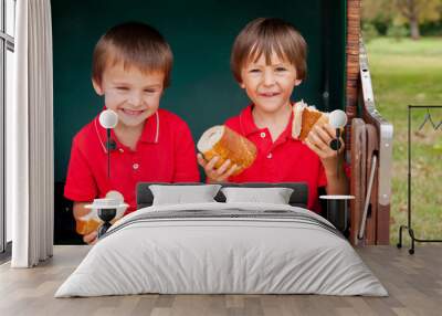 Two kids, sitting in a sheltered bench, eating sandwiches Wall mural