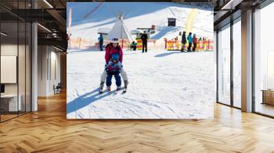 Young mother, teaching her preschool child to ski, sunny winter day Wall mural