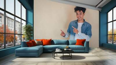 Young curly man wear denim clothes with happy face. Show the click the copy space. The photo is suitable to use for click thumbnail product and ecommerce promotion. Wall mural